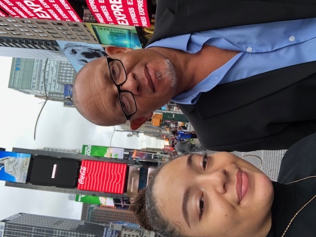 Two people wearing sunglasses smiling outdoors on a sunny day.
